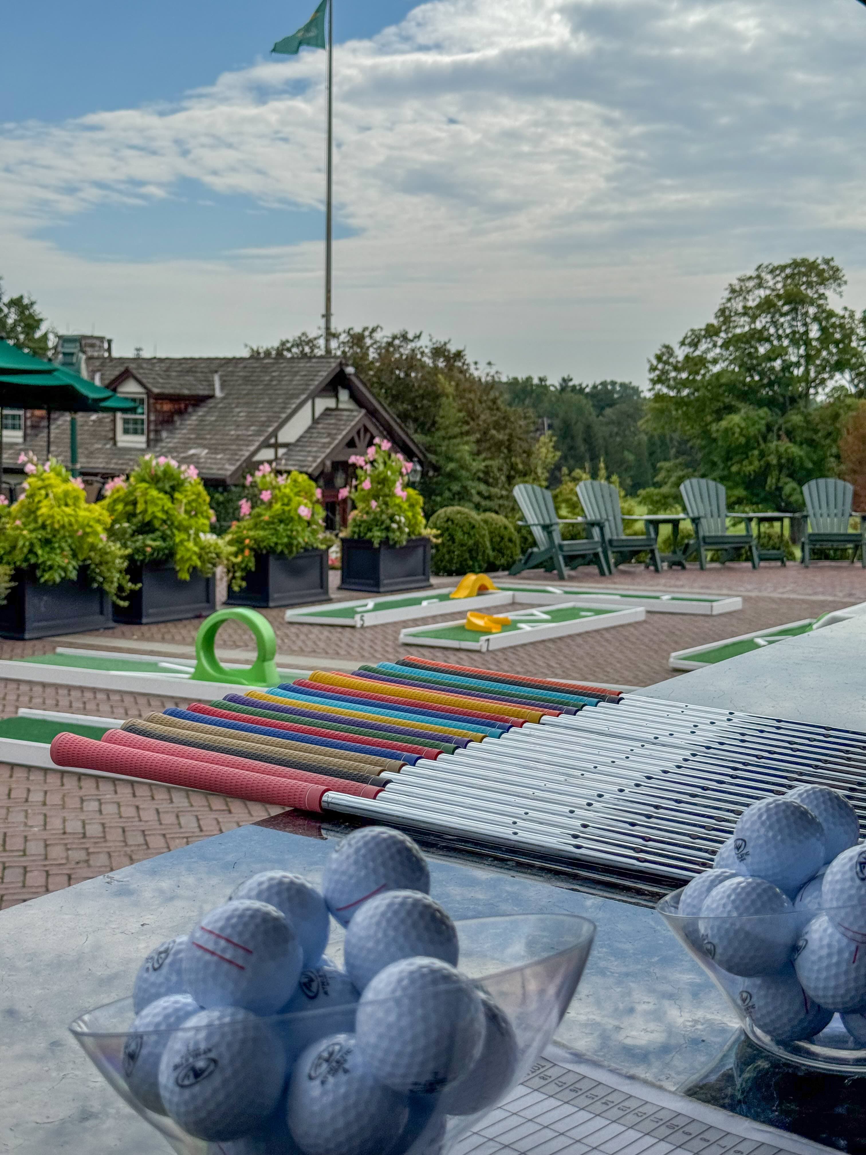 Colorful golf putters and balls staged at a country club mini golf setup
