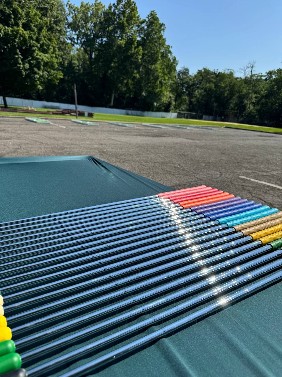 Rainbow of colorful mini golf putters lined up on the course